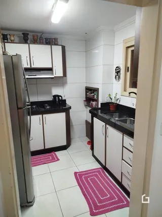 Uma cozinha com armários brancos e piso cerâmico claro.
