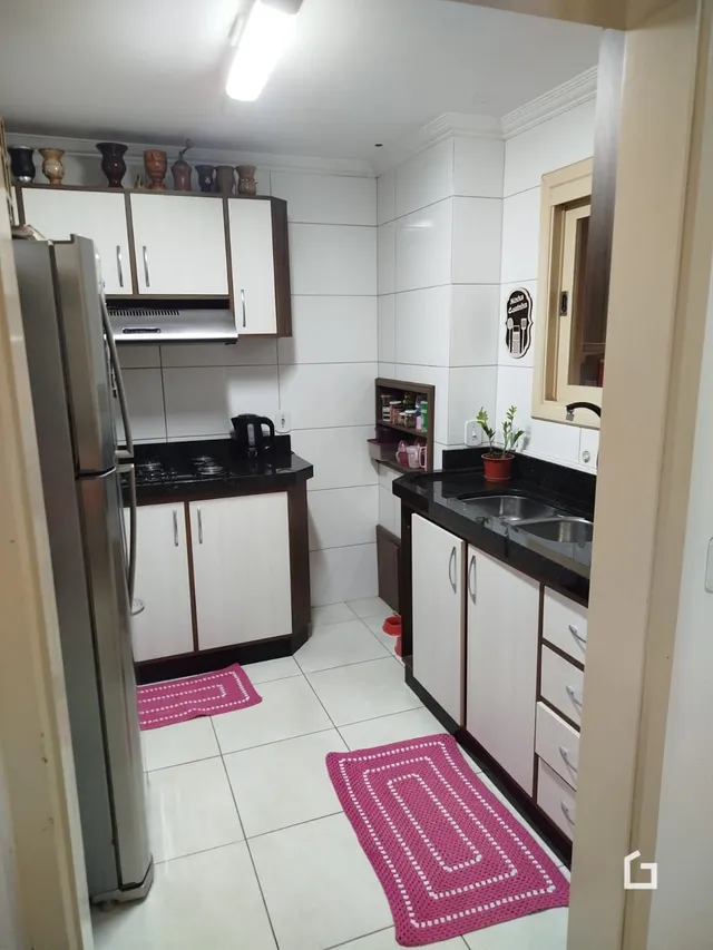 Uma cozinha com armários brancos e piso cerâmico claro.