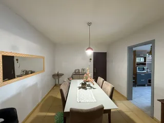 Uma sala de jantar com mesa e cadeiras em um ambiente claro.