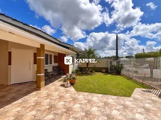Fachada de uma residência em Lajeado, Brasil, mostrando o pátio de pedras e o jardim gramado.