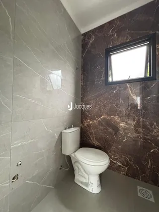 Foto de um banheiro com revestimento de azulejo e vaso sanitário.