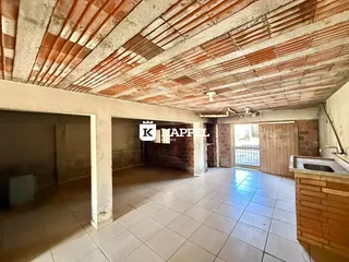 Vista interna de um cômodo com teto de telhas expostas e piso de cerâmica clara.