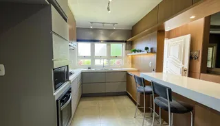 Vista interna de uma cozinha com armários de madeira e bancada clara.