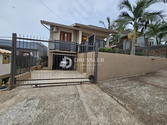 Fachada de uma residência em Lajeado, Brasil, com portão de ferro e muro.