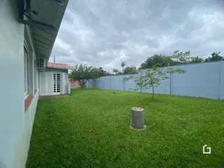 Vista da fachada de uma residência com jardim gramado e cerca branca.