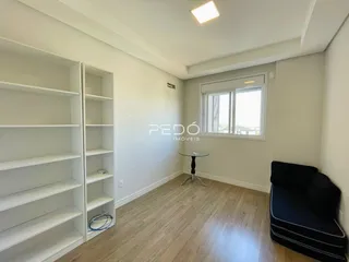 Sala de estar com piso de madeira e estantes brancas.