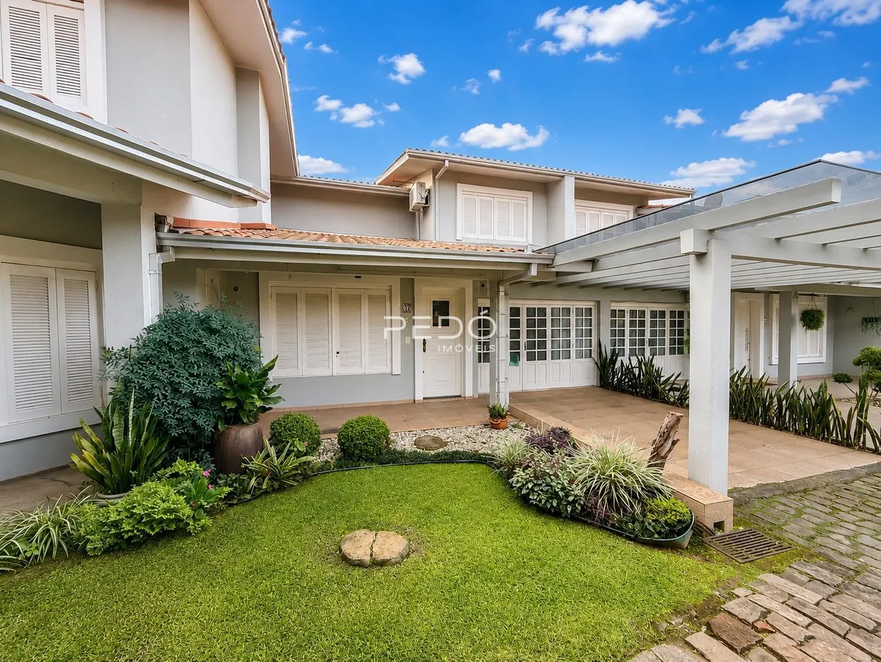 Foto da fachada de uma residência em Lajeado, Brasil, com jardim frontal bem cuidado.