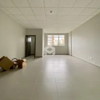 Vista interna de uma sala ampla com piso de cerâmica e teto de gesso.
