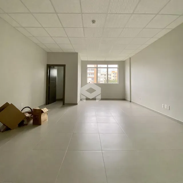 Vista interna de uma sala ampla com piso de cerâmica e teto de gesso.