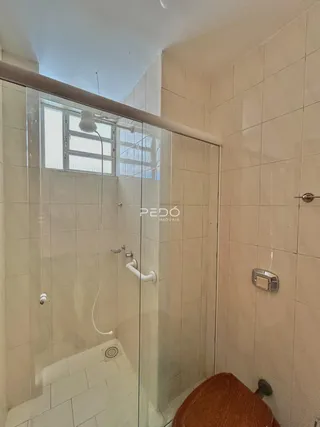 Foto de um banheiro com box de vidro e revestimento de cerâmica clara.