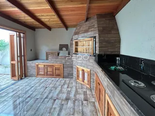 Ambiente interno de uma sala de estar com detalhes em madeira e parede de pedra.