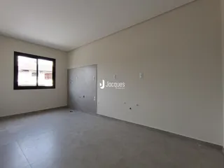 Uma sala vazia com paredes brancas e piso de concreto.