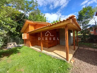 Fachada de uma casa de madeira com telhado de telhas em um ambiente com gramado.