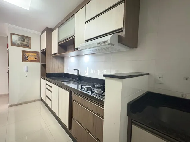 Cozinha com armários de madeira e bancada escura.