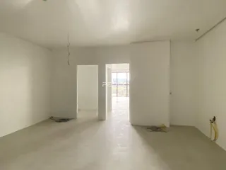 Uma sala ampla e vazia com paredes brancas e um vão de porta.
