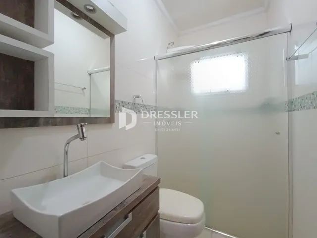 Foto de um banheiro com box de vidro e pia.