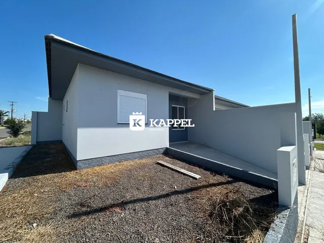 Fachada externa de uma casa simples em Lajeado, com jardim seco.