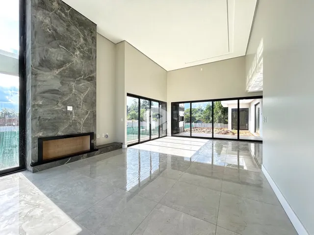 Interior de uma sala ampla com piso de porcelanato e grandes portas de vidro.