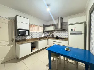 Vista da cozinha com armários brancos e bancada de granito.