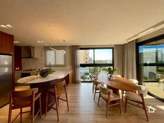 Interior de uma sala de estar com mesa de jantar e cozinha em um apartamento.