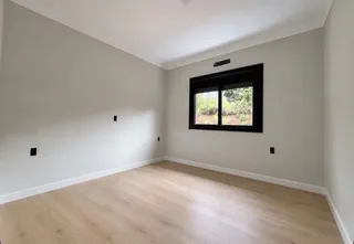 Uma sala de estar com piso de madeira clara e uma janela.