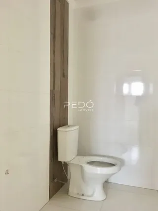 Foto de um banheiro interno com vaso sanitário branco e parede de madeira.