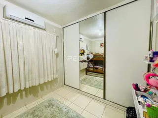 Uma sala interna com piso de cerâmica e cortinas brancas.
