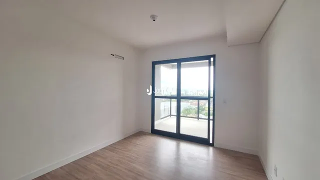 Ambiente interno de uma sala com piso de madeira e parede branca.