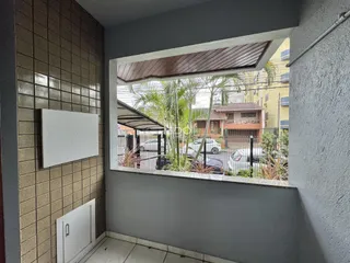 Vista de uma área interna com parede de azulejos e abertura para o exterior de uma residência.