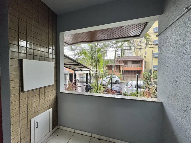 Vista de uma área interna com parede de azulejos e abertura para o exterior de uma residência.