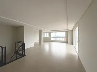 Interior de um espaço amplo com piso claro e paredes brancas.