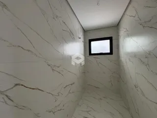 Corredor interno com paredes em mármore branco e uma janela.
