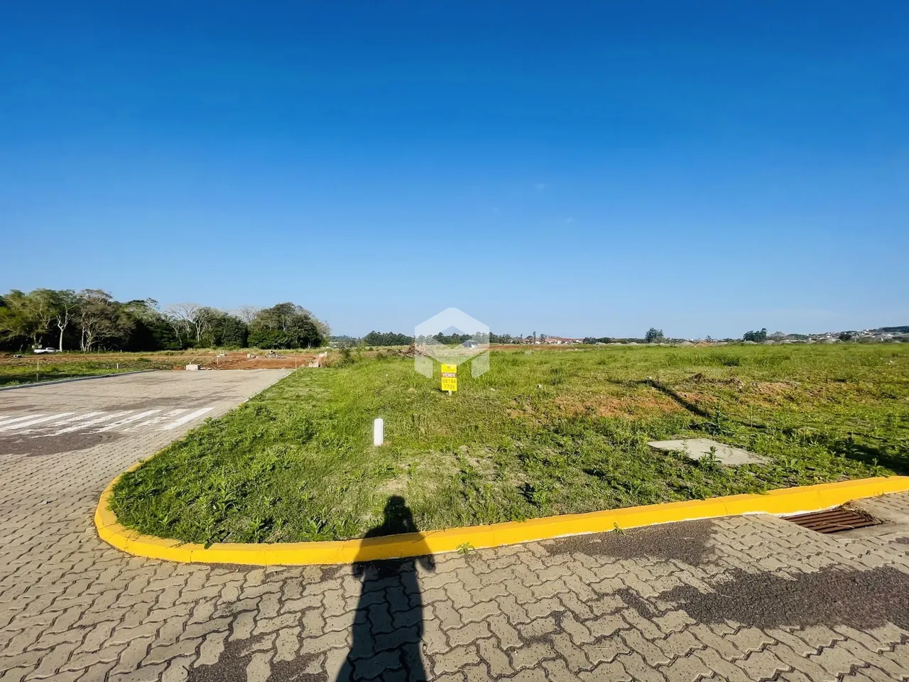 Vista externa de uma propriedade com área gramada e pavimento.