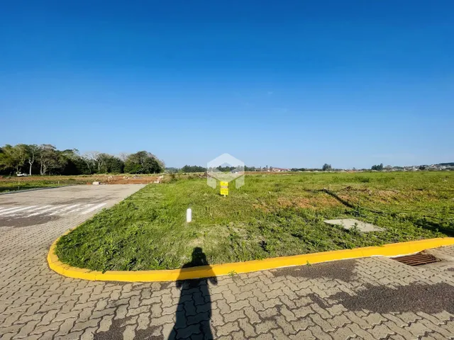 Vista externa de uma propriedade com área gramada e pavimento.