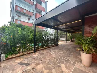 Pátio externo com piso de pedra e vegetação ao lado de um prédio residencial.