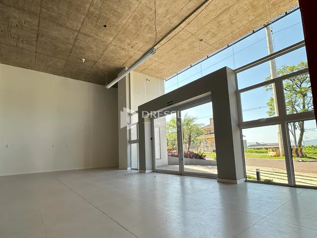 Ambiente interno amplo com grandes janelas de vidro e teto de concreto.