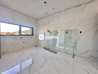 Interior de um ambiente com piso de mármore branco e parede de vidro.