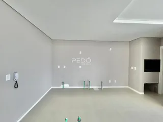 Ambiente interno de uma sala ampla com paredes cinzas e piso claro.