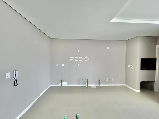 Ambiente interno de uma sala ampla com paredes cinzas e piso claro.