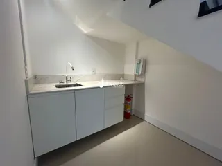 Vista de uma cozinha moderna com armários brancos e bancada clara.