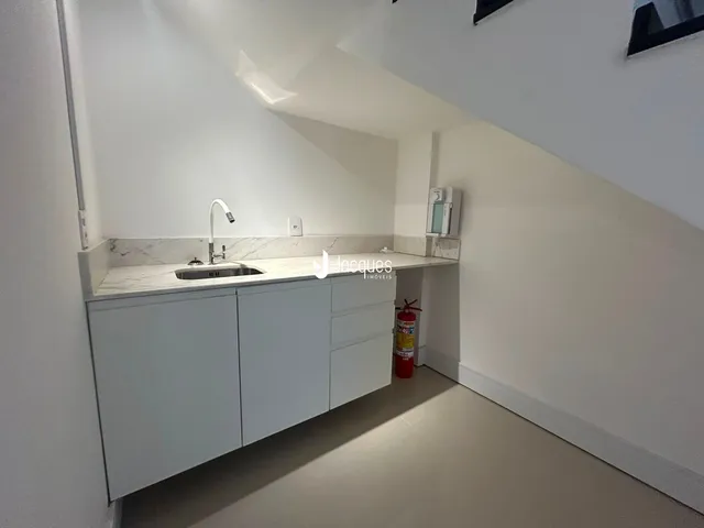 Vista de uma cozinha moderna com armários brancos e bancada clara.