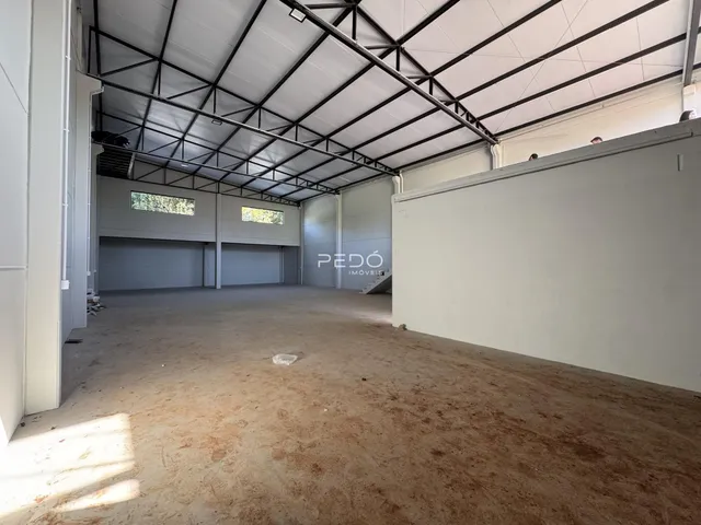Interior de um espaço amplo com estrutura de telhado exposta e portas de garagem.