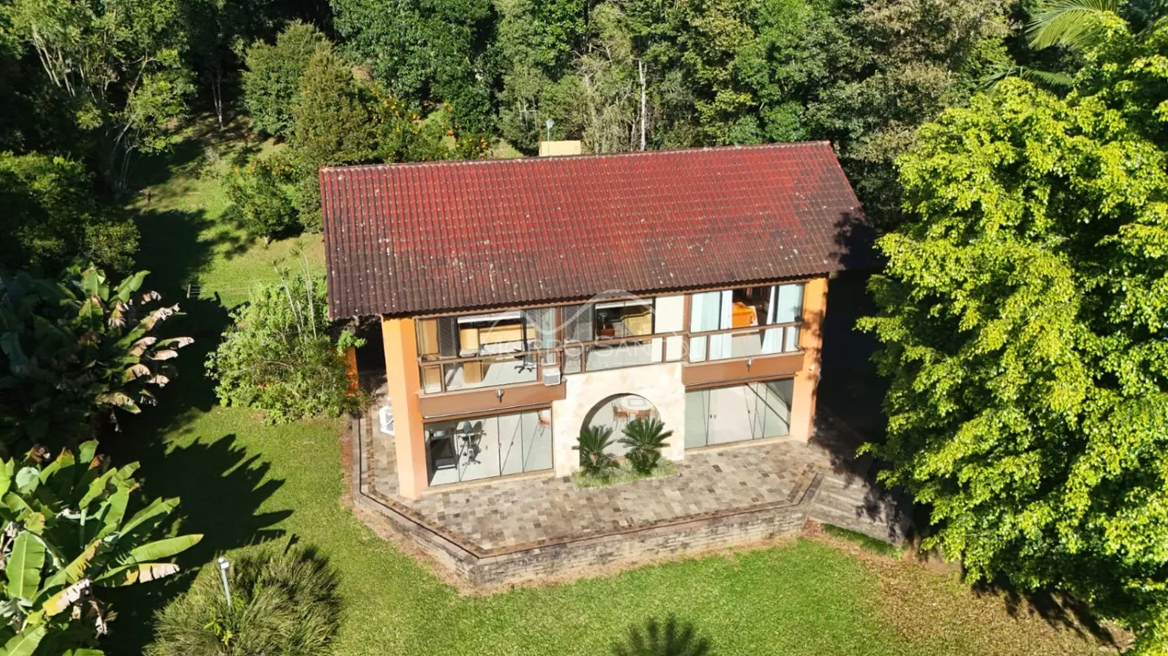 Foto aérea da fachada de uma casa em Lajeado, Brasil, cercada por vegetação exuberante.