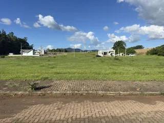 Foto da fachada de uma propriedade rural com campo verde ao fundo.