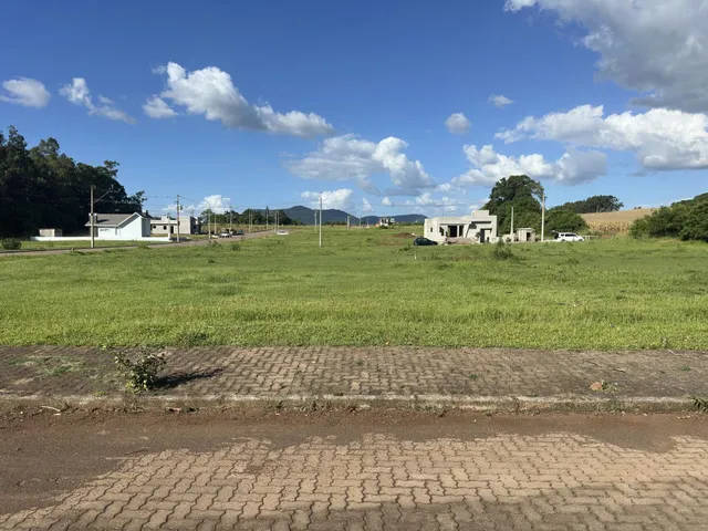 Foto da fachada de uma propriedade rural com campo verde ao fundo.