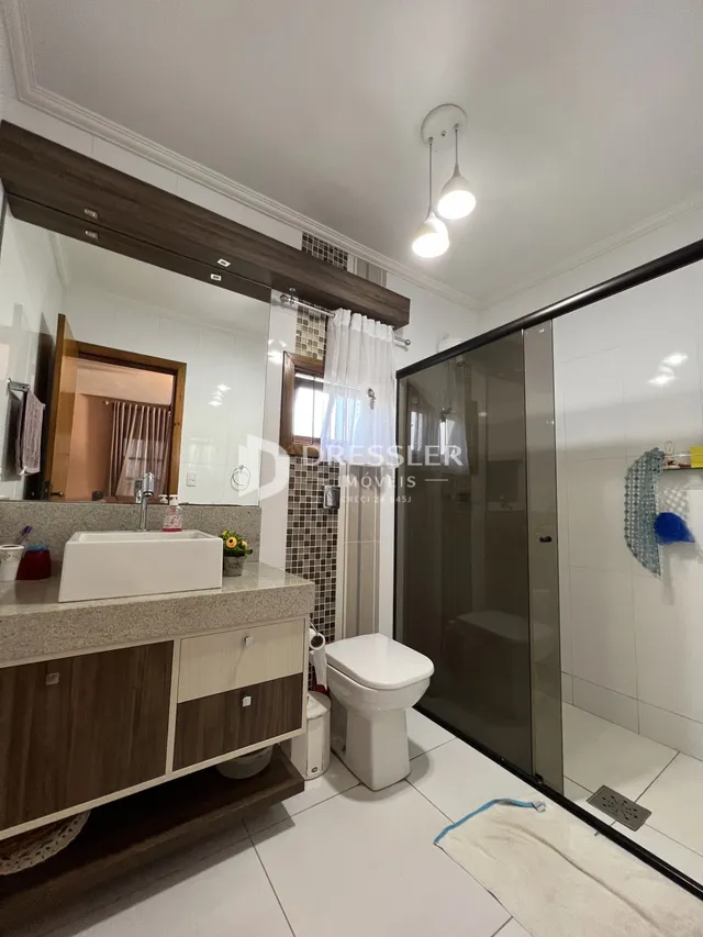 Foto de um banheiro moderno com box de vidro e louças brancas.