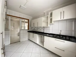 Cozinha moderna com armários brancos e piso de cerâmica clara.
