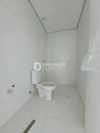 Foto do interior de um banheiro com revestimento branco.