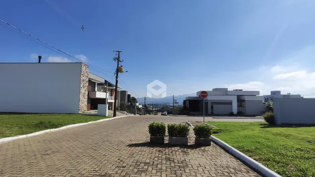 Vista externa de uma propriedade com jardim e área pavimentada.