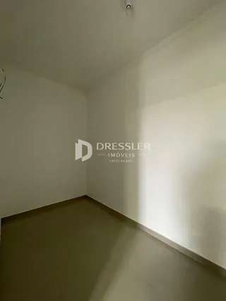 Vista interna de um cômodo com paredes brancas e piso claro.